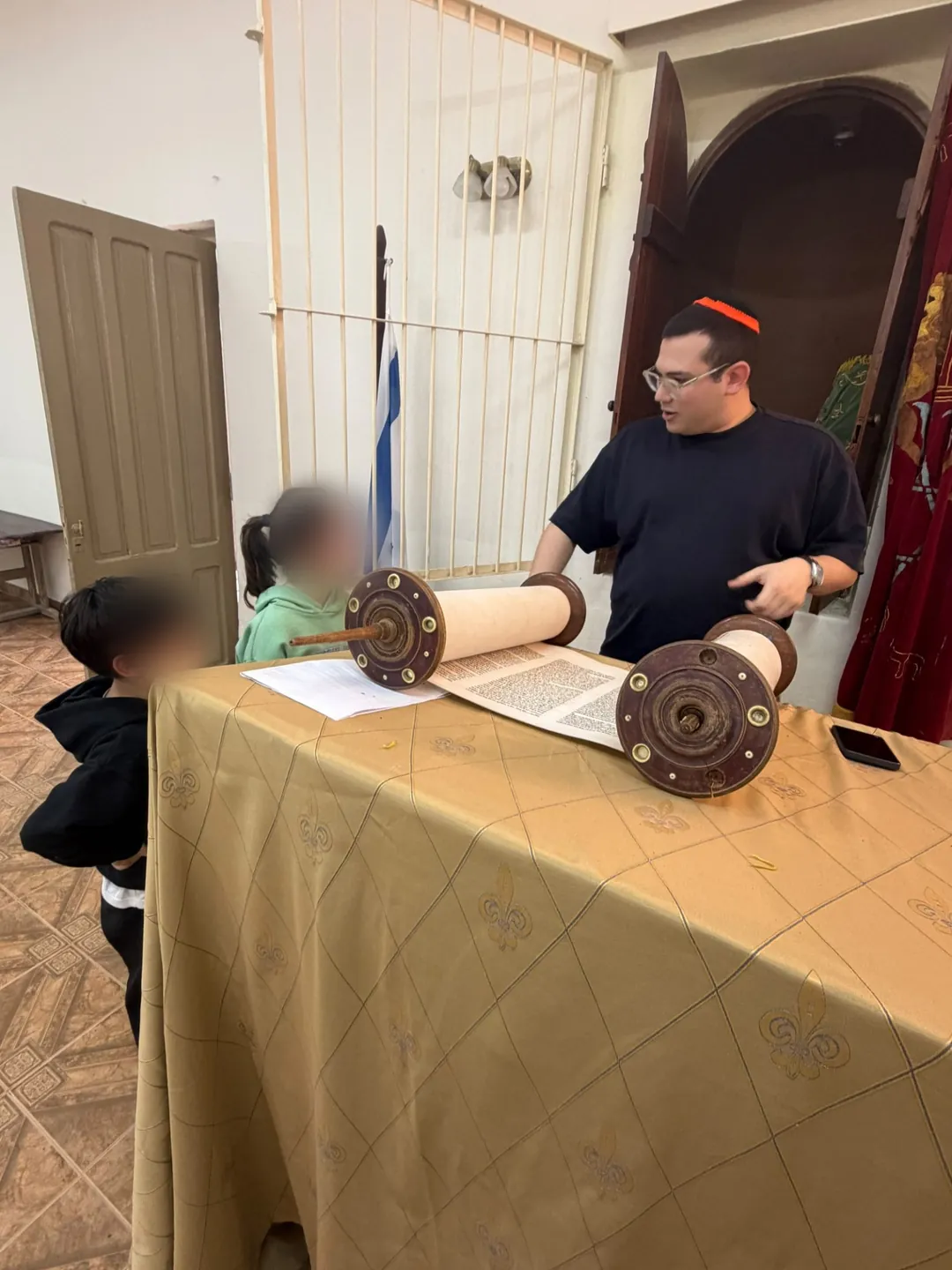 Mati showing the open sefer to two kids